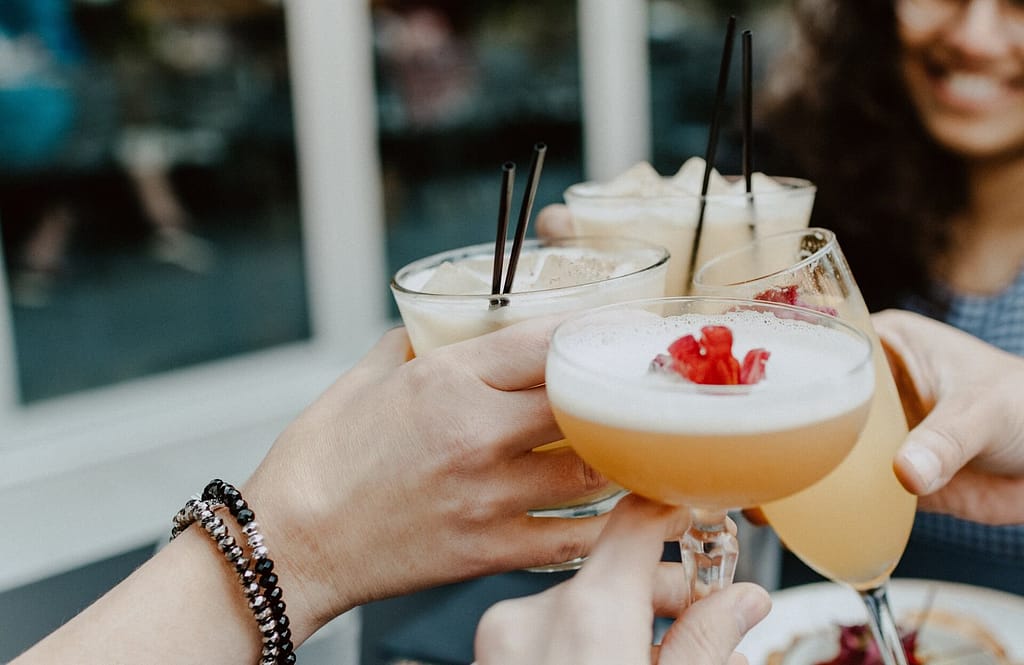 Three cocktail drinks are being clinked together to celebrate