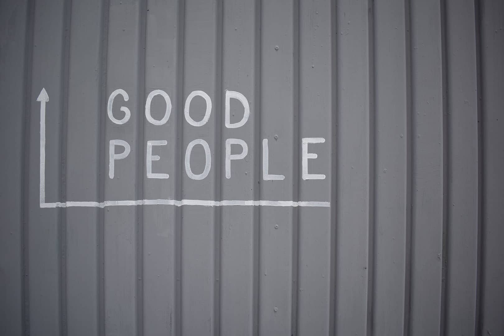 Grey panel board back ground with the words Good People in capitals to the left. With an arrow under the words and then pointing upwards.